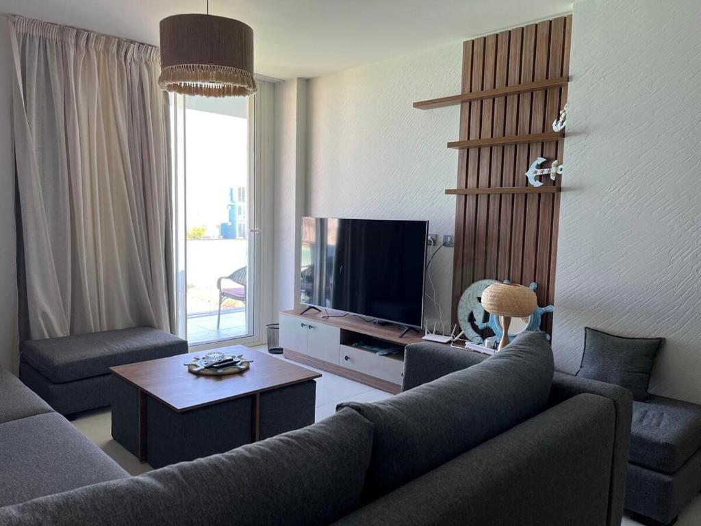 a living room with a couch and a tv at Charming Fouka bay 3bd direct lagoon view Chalet for Families Only or Group of Girls in Marsa Matruh