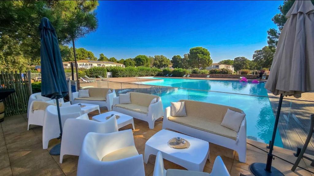 - une piscine avec des chaises blanches et un parasol dans l'établissement Fiori di Cala Rossa résidence hôtelière, à Lecci