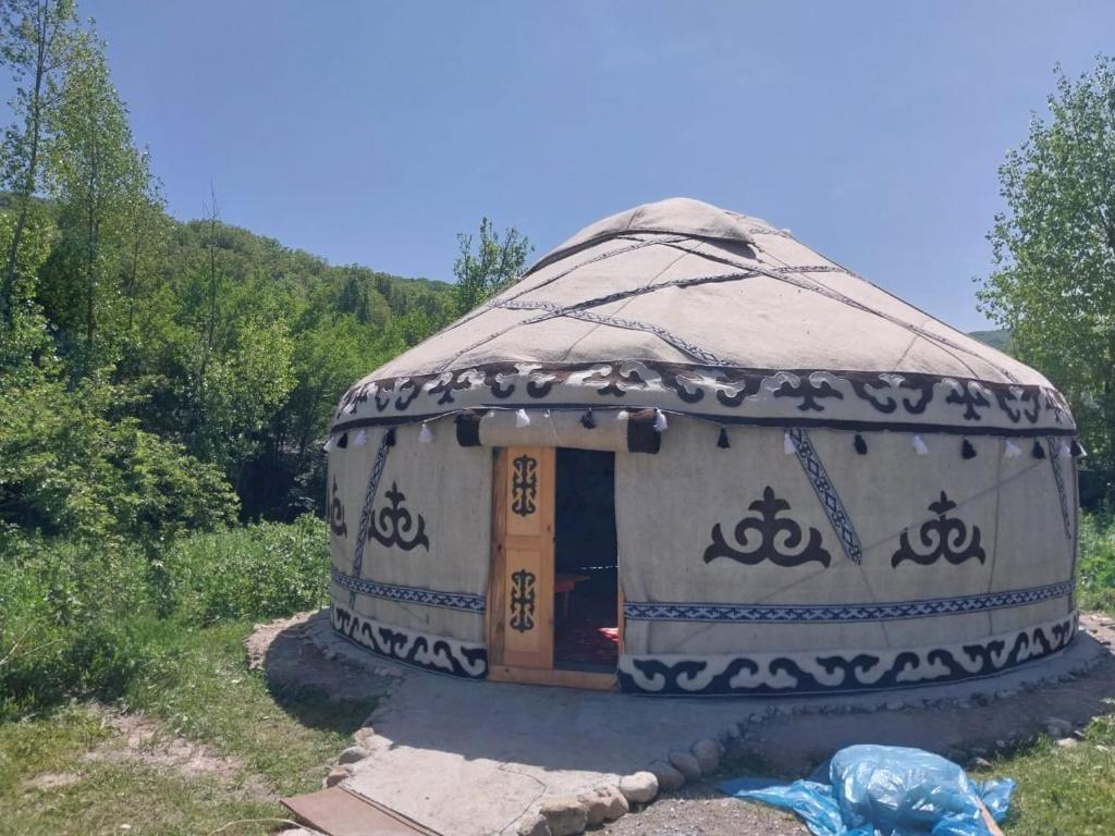 a large yurt with a door in the grass at Guest house Shairkul in Kyzylunkyur