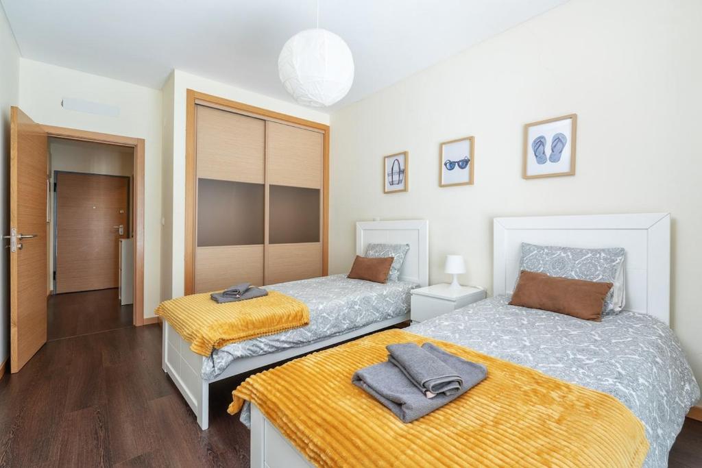 - une chambre avec 2 lits avec des draps jaunes dans l'établissement Vacances Tranquilles, à Olhos de Água