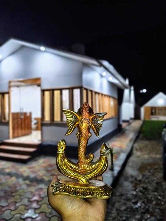 a hand holding a gold dragon statuette in front of a house at Blue Sheep Resort & Restaurant in Nākuri