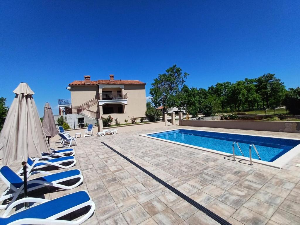 a swimming pool with lounge chairs and a house at Apartman Aurora Salakovci in Labin