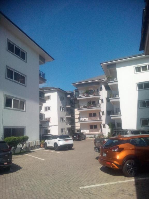 a parking lot with cars parked in front of buildings at Diamond Ridge Apartments in Accra