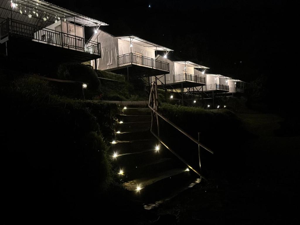 ein beleuchtetes Gebäude mit Treppe und Lichtern bei Nacht in der Unterkunft Escape Pod Himalayan Campsite in Bhīm Tāl
