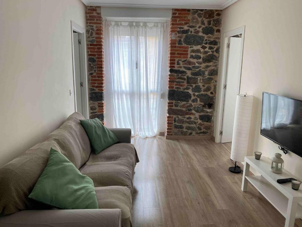 una sala de estar con un sofá y un televisor en Precioso piso 1 muy cerca de la playa de Salinas, en Piedras Blancas