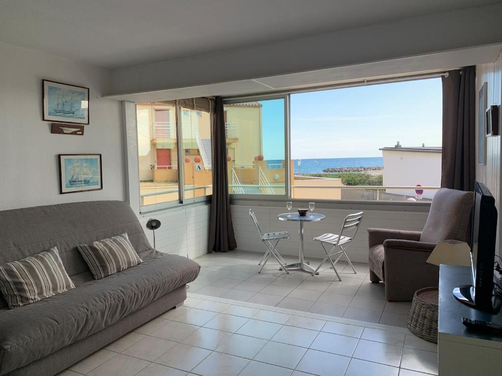 un salon avec un canapé et une table dans l'établissement Spacieux studio vue mer sur le port, à Frontignan