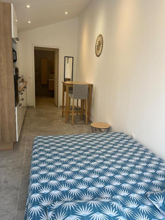 - une chambre avec un lit bleu et blanc et une table dans l'établissement Studio L'Essentiel, à Istres