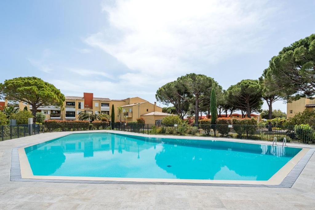 une piscine avec des arbres et des bâtiments en arrière-plan dans l'établissement Le Mountadou par Dodo à Cassis, à Cassis
