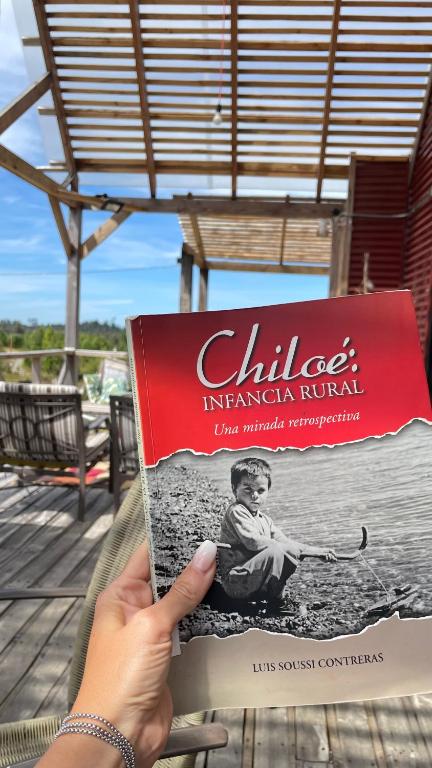 a person holding a book in their hand at Casa Chiloe in Penanes Bajo