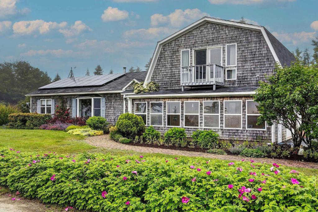 a house with a balcony and flowers in the yard at Bay Views Peaceful Acadia National Park Getaway! in Steuben