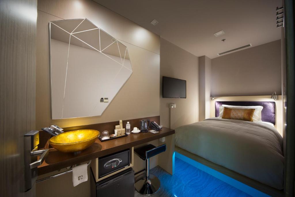 a bedroom with a bed and a sink and a mirror at Hotel Clover 7 in Singapore