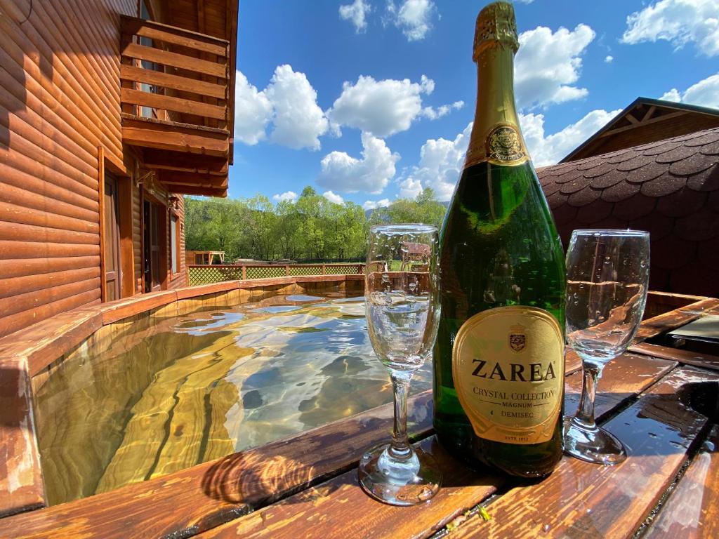 a bottle of wine and glasses on a table next to a swimming pool at La Cabane Râșnov Spa and Retreat in Râşnov