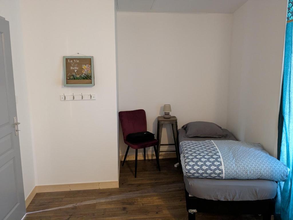 una piccola camera con letto e sedia di Chez Cornélia a Estaing
