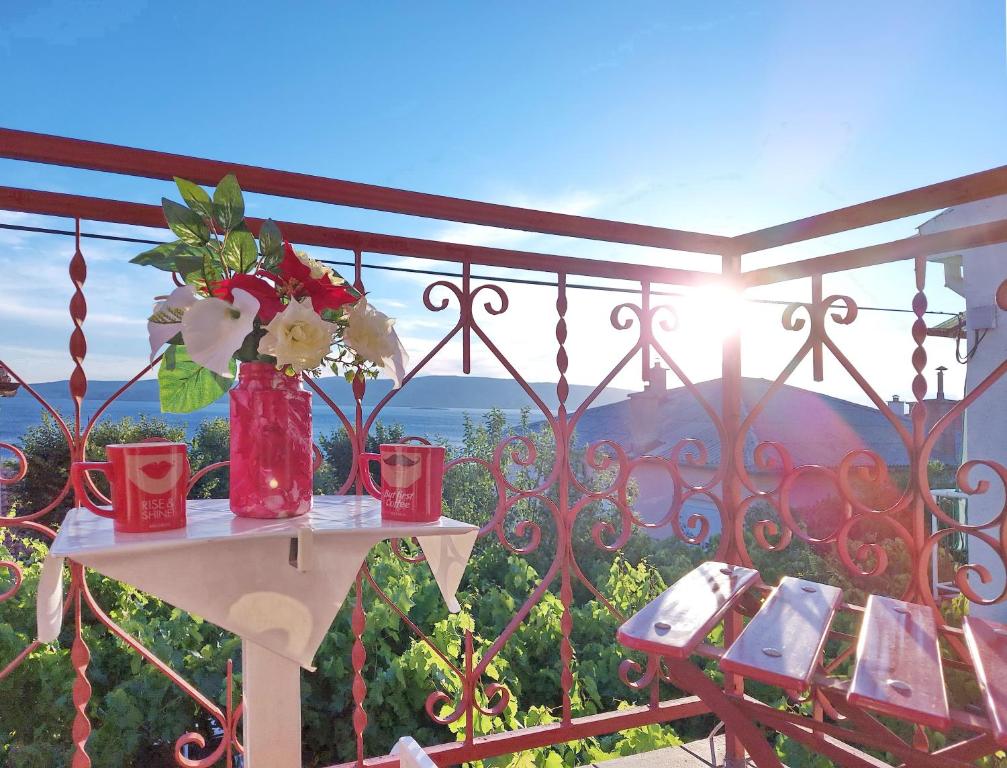 a table with a vase of flowers on a balcony at Holiday House Jure in Senj