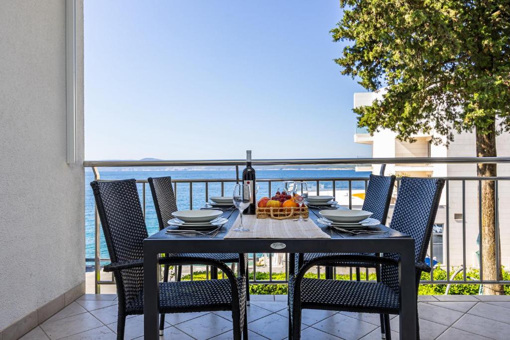 a table with chairs and a bowl of fruit on a balcony at Apartmani Heta Alagic I in Selce