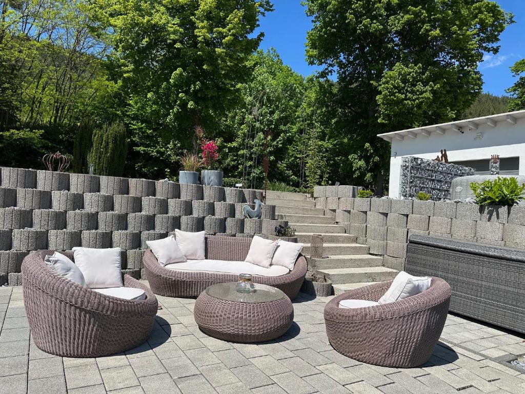 a patio with wicker chairs and a table and stairs at Dorfperle in Oberzent