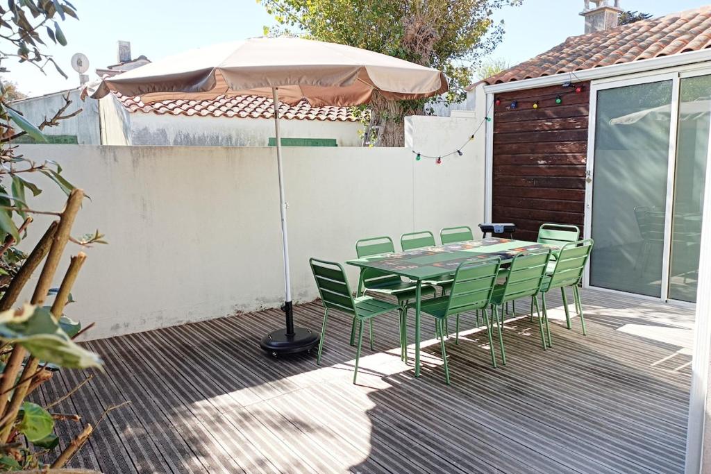 une table et des chaises avec un parasol sur une terrasse dans l'établissement Maison plage à 100 mètres et piste cyclable à 40 mètres, à Dolus-d'Oléron