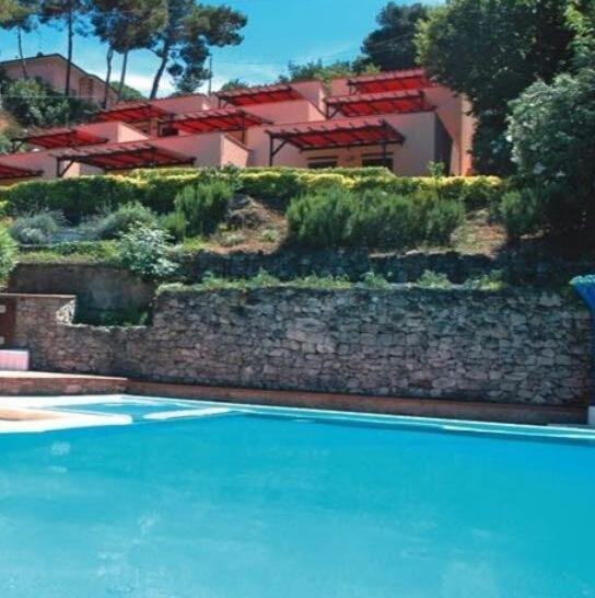 a stone wall next to a blue swimming pool at Residence Vistamare La Fonte in Nisporto