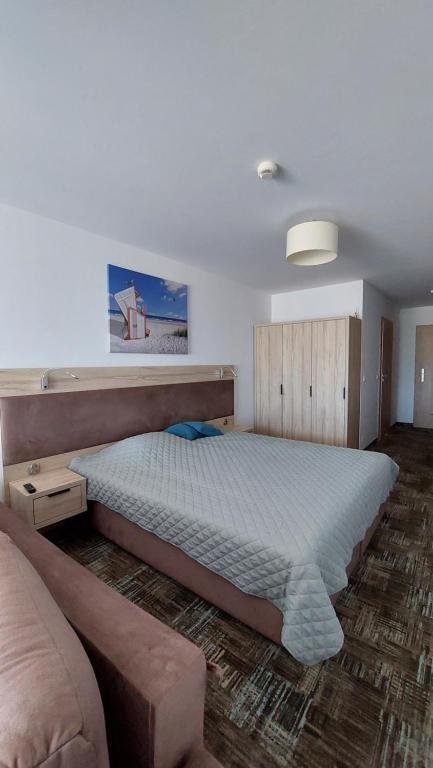 a bedroom with a large bed and a couch at Apartament Sand Welle in Grzybowo
