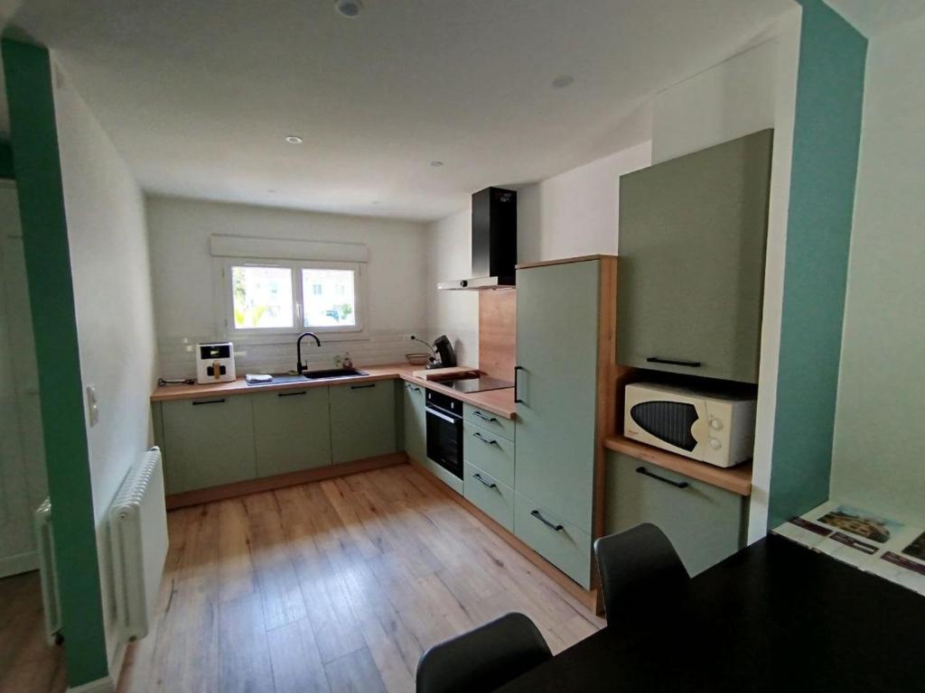 Il comprend une cuisine avec des placards verts et du parquet. dans l'établissement Maison 3 chambres Le Mans, au Mans
