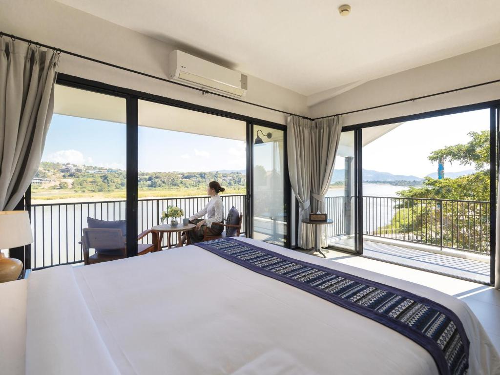 una camera con un grande letto e un balcone di Fortune Riverview Hotel Chiang Khong a Chiang Khong
