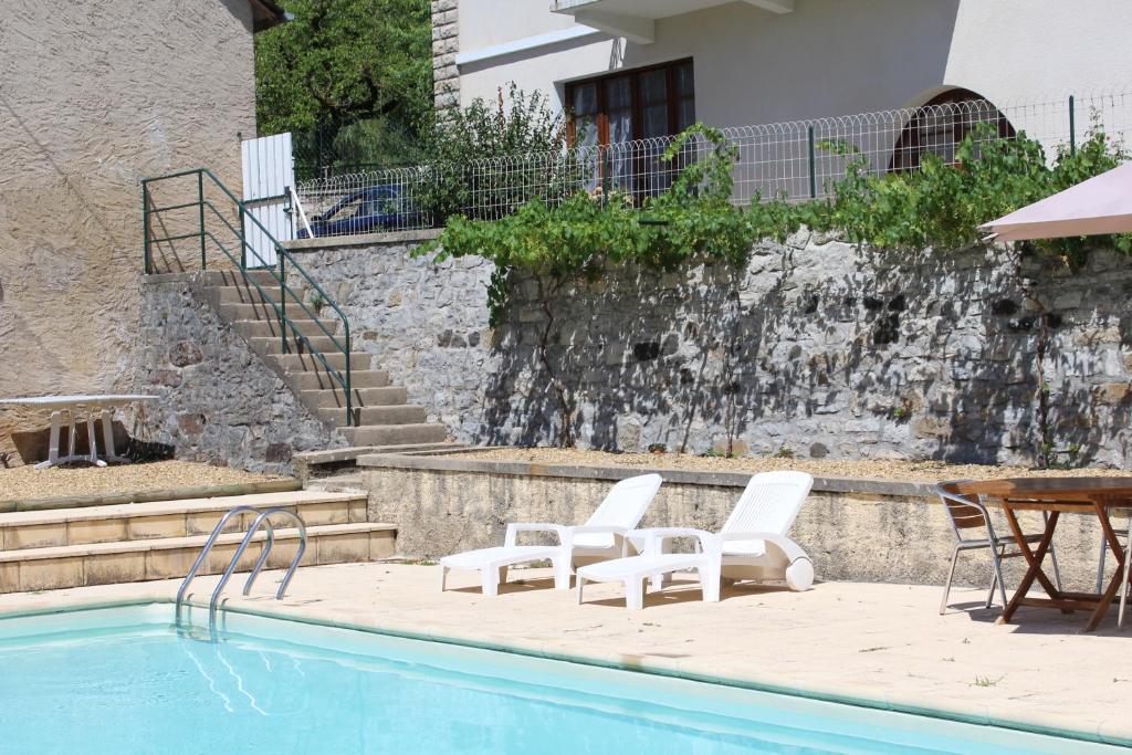 a pool with two chairs and a table and a table and chairsitures at Chambres d'hôtes La Fontaine in Espalion