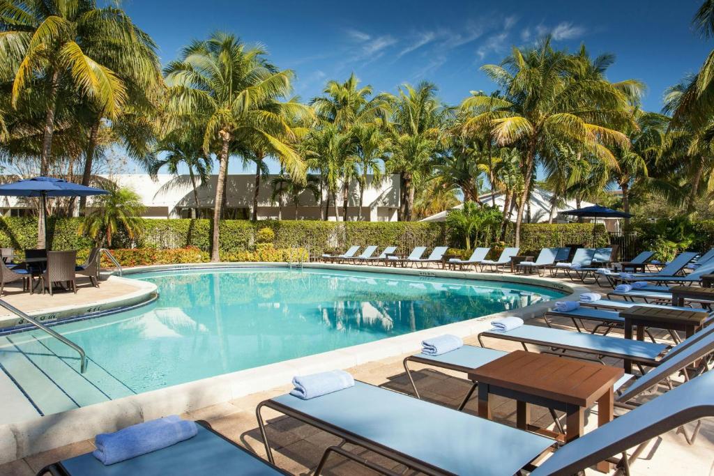 a swimming pool with lounge chairs and palm trees at West Palm Beach Marriott in West Palm Beach