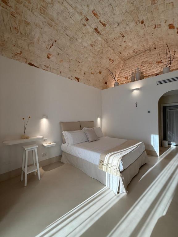 a white bedroom with a bed and a table at La Volta in Locorotondo