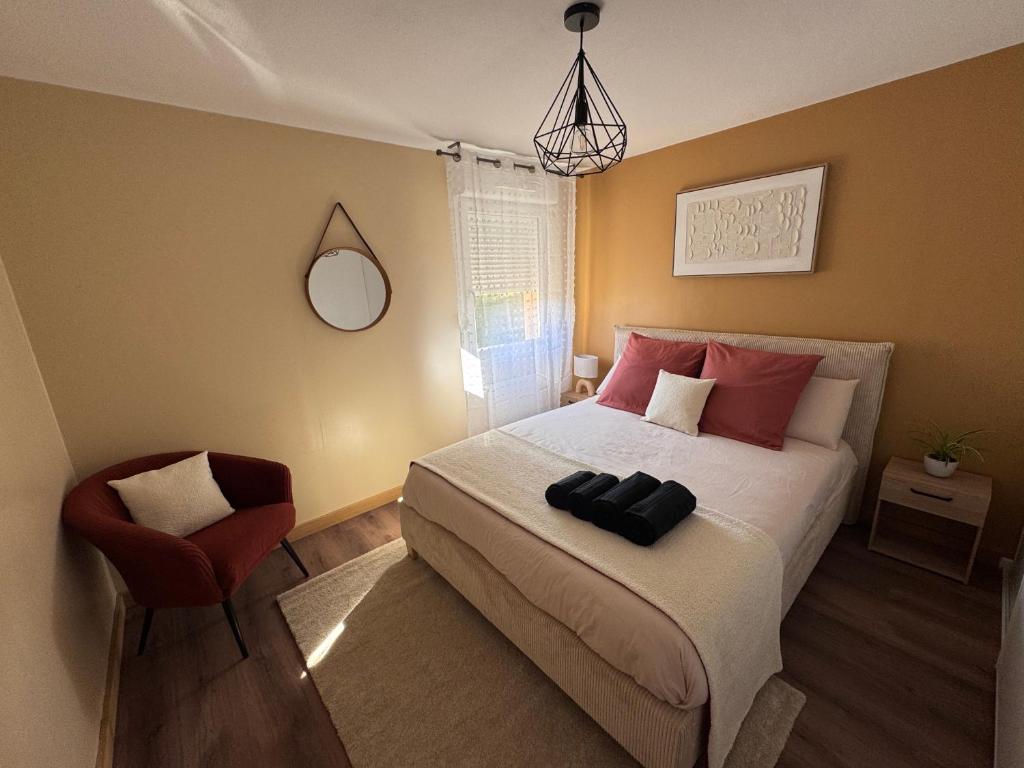 a bedroom with a bed and a red chair at Le Terracotta - Parking privé in Langres