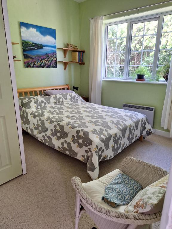 a bedroom with a bed and a chair and a window at 2 White Horse Cottages in Washford