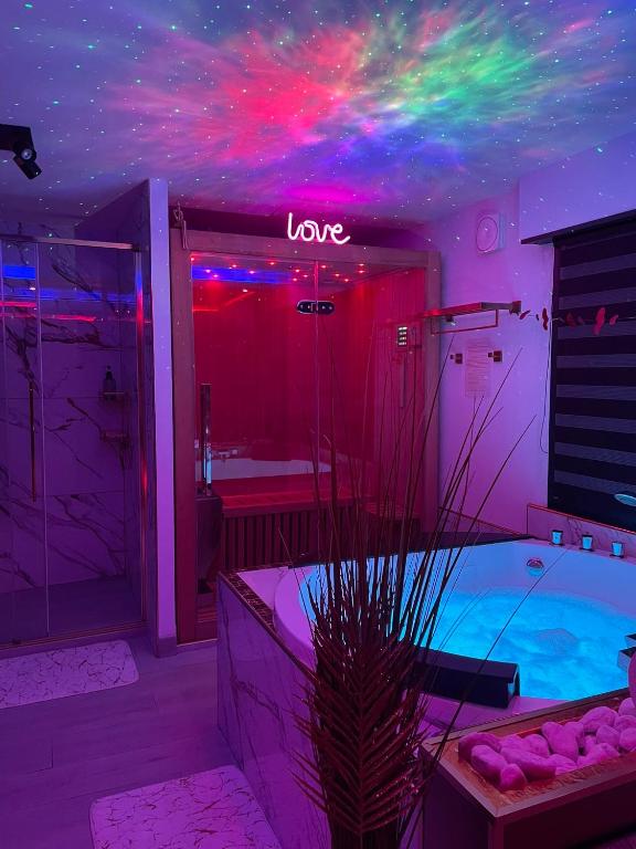 une pièce avec une baignoire et une enseigne au néon au plafond dans l'établissement L'Aurore suite de charme, clim jacuzzi, sauna, piscine chauffée cuisine..., à Carpentras