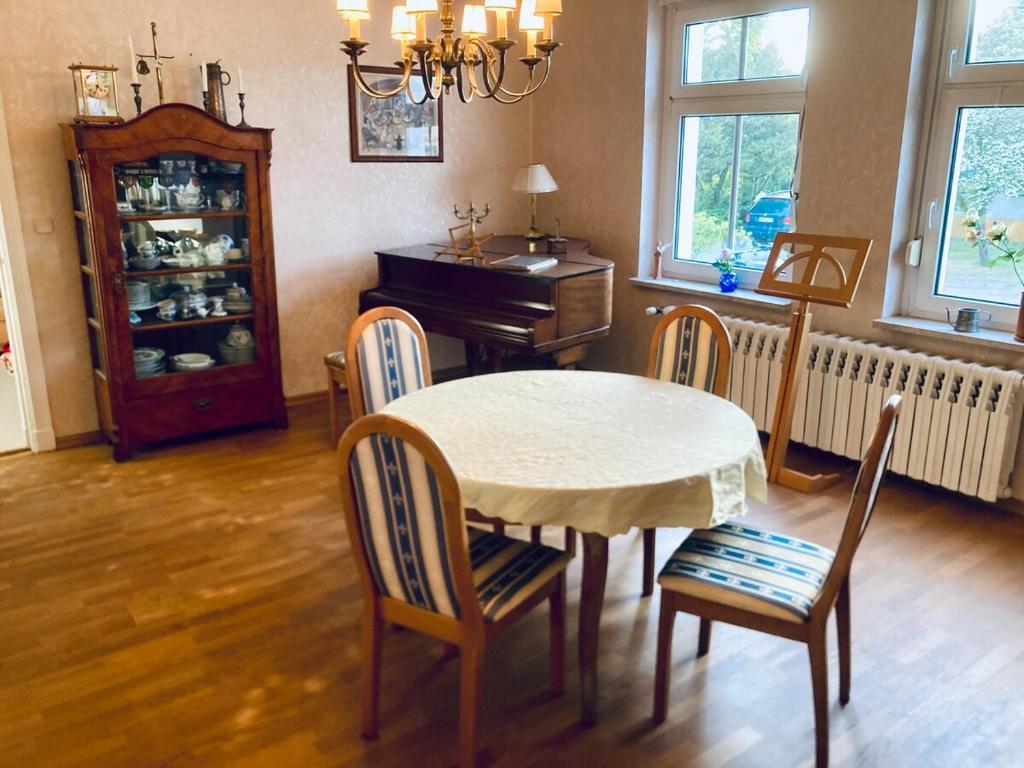 a dining room with a table and chairs and a piano at Naturidylle mit Kamin und Sauna in der Schorfheide in Schorfheide
