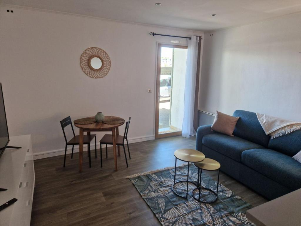 un salon avec un canapé bleu et une table dans l'établissement Charmant studio Arlésien en bordure du Rhône, à Arles