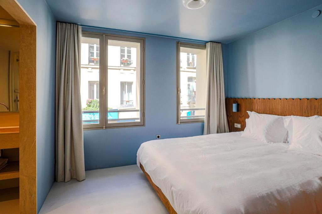 a blue bedroom with a bed and two windows at Suite d'exception Marais in Paris