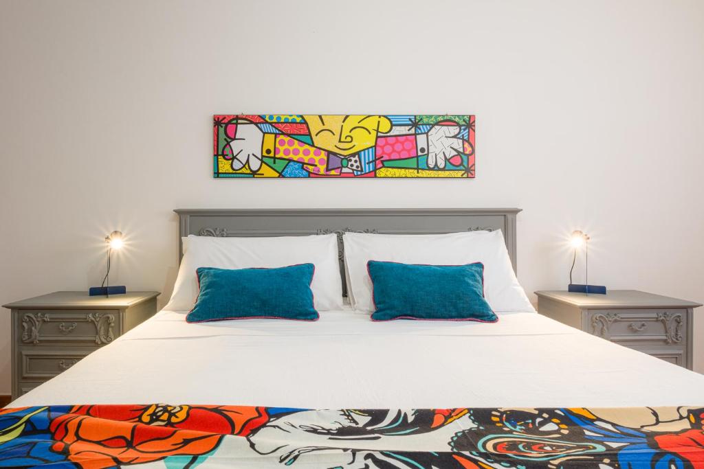 ein Schlafzimmer mit einem weißen Bett mit blauen Kissen in der Unterkunft Pietrenere39 in Pozzallo