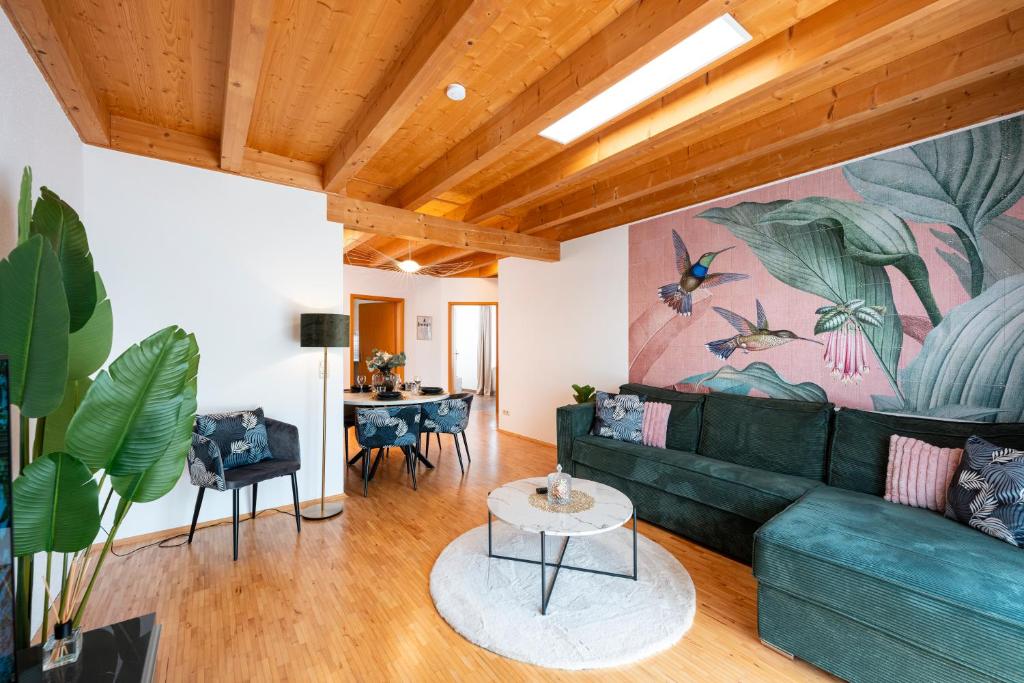 a living room with a green couch and a table at NAMASTÉ Homes - Ferienwohnung mit Balkon & Carport in Bad Windsheim