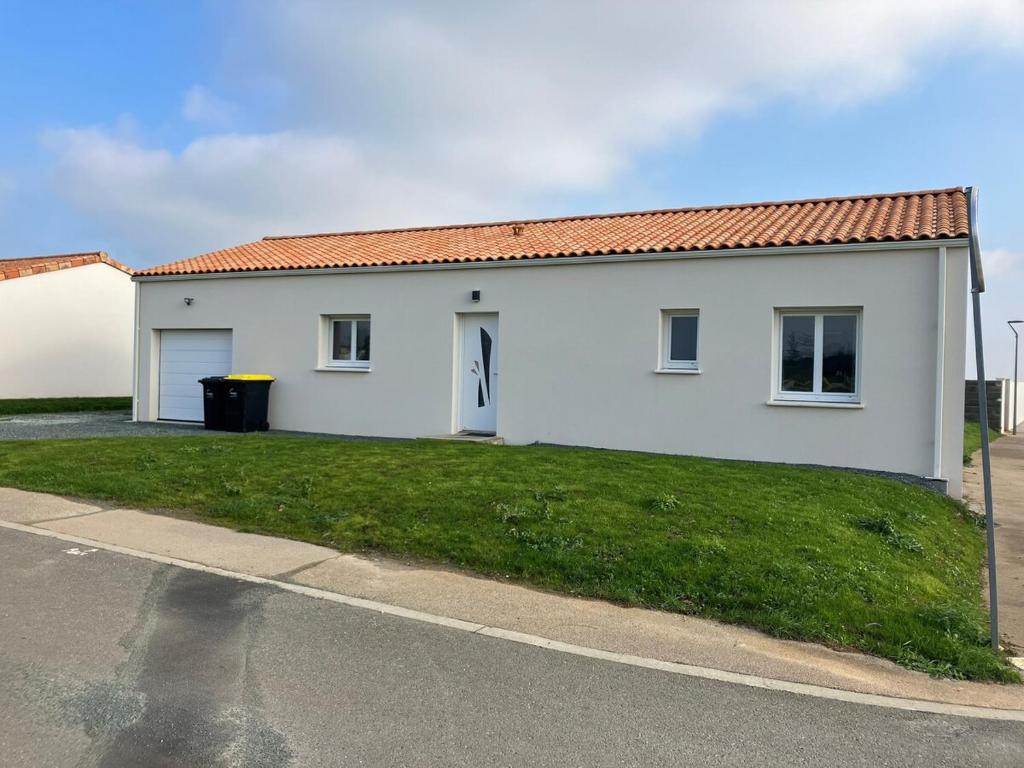 une maison blanche avec une pelouse verte devant elle dans l'établissement Maison 6 personnes, à Pétosse