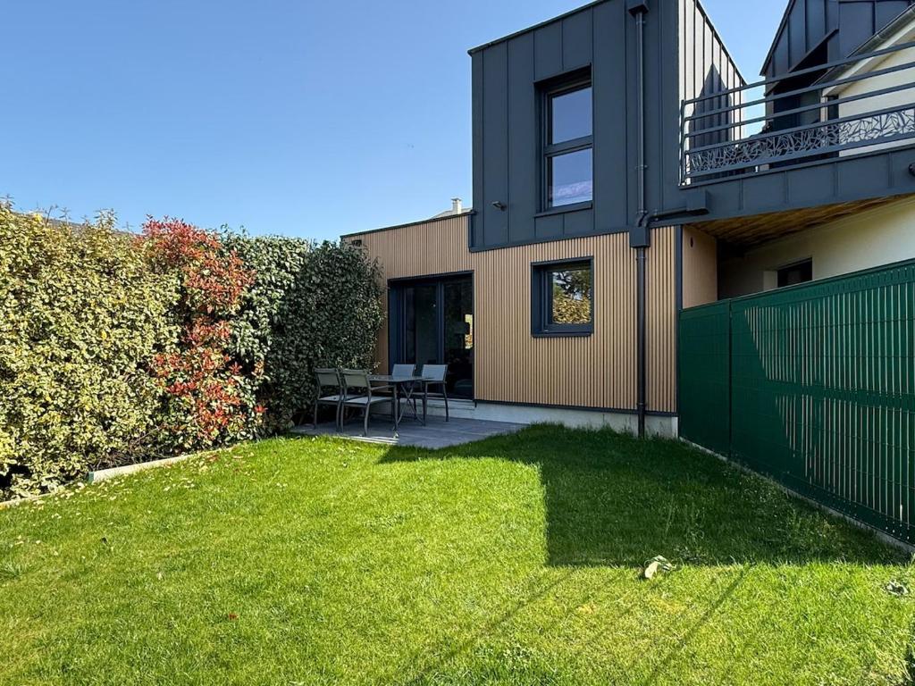 a house with a green fence and a yard at La Maison d'à Coté in Saint-Jean-le-Blanc