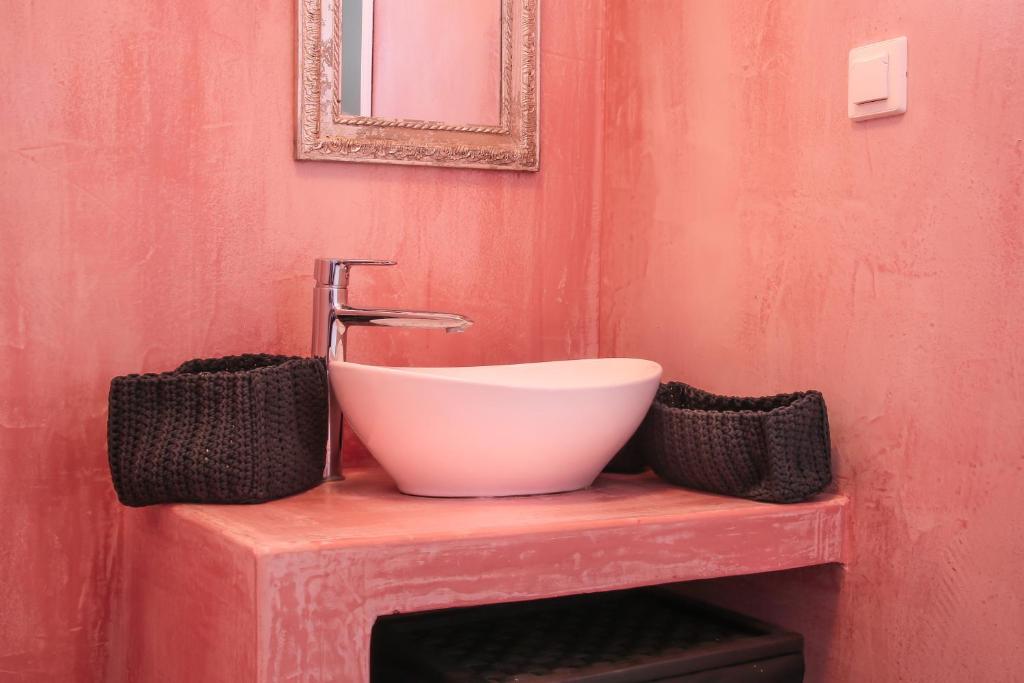 a bathroom with a white sink on a red wall at Camara Homes in Andros