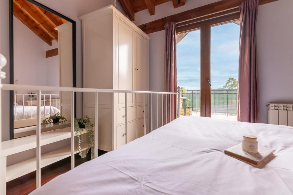 a bedroom with a bed and a large window at Duplex cerca de la playa con piscina in Miengo