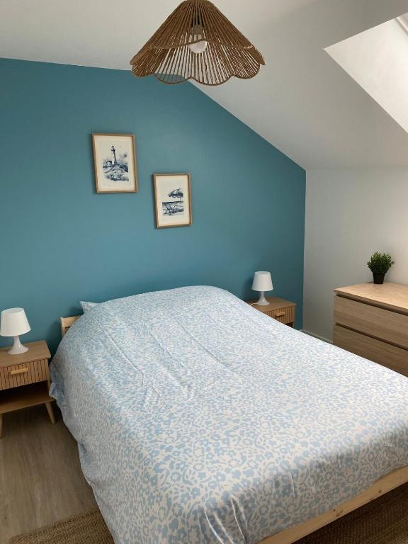 une chambre avec un mur bleu et un lit dans l'établissement Maison cosy à Aure sur Mer, à Sainte-Honorine-des-Pertes