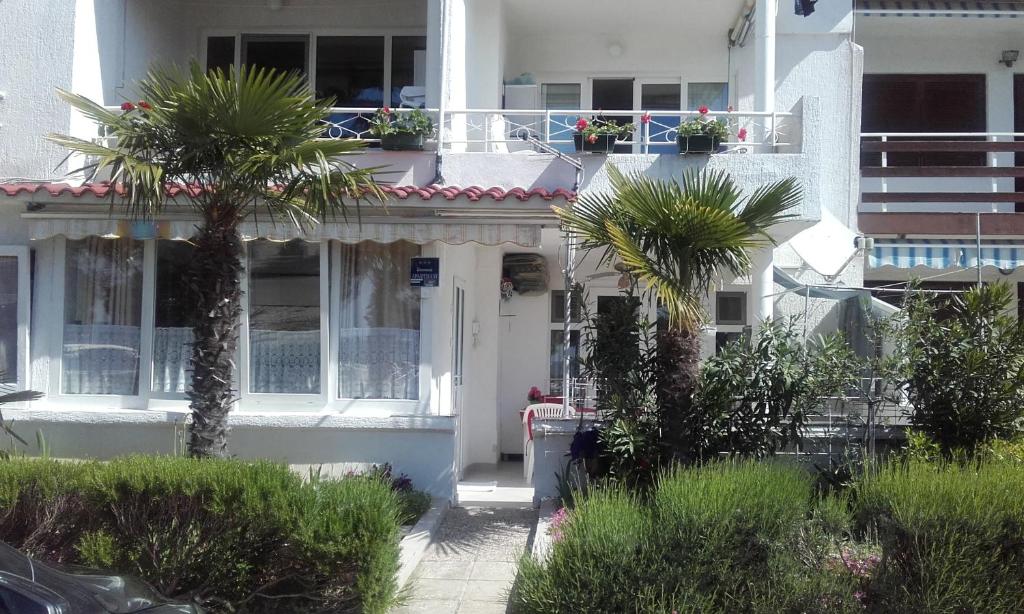a white house with palm trees in front of it at Apartments Aleksandra in Crikvenica