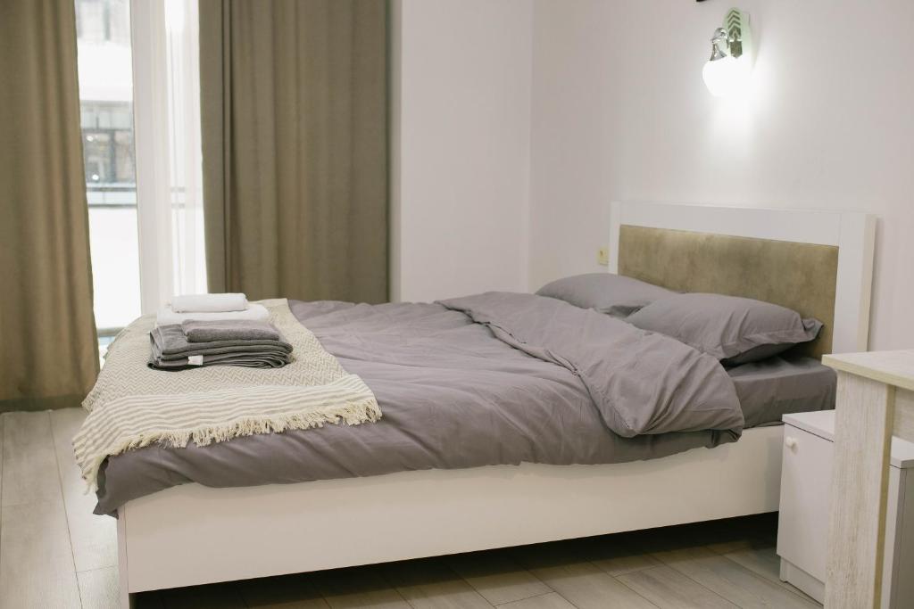 un letto bianco con lenzuola e cuscini grigi; di Lumari Apartment a Kakhaberi