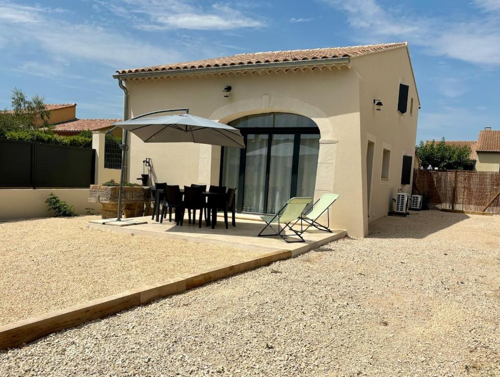 une maison avec une table et un parasol dans l'établissement Maison rénovée 3 chambres, à Mollégès