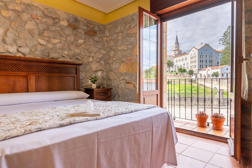 a bedroom with a bed and a large window at Apartamentos El Cruce de Moratón in Cóbreces
