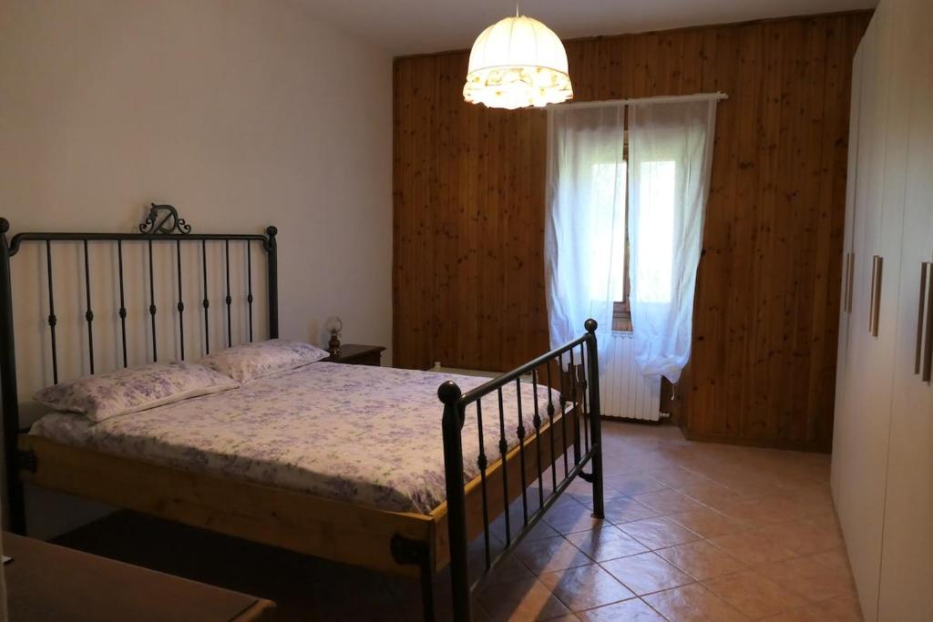 a bedroom with a bed and a window and a chandelier at Rosso Papavero Home in Borgo San Lorenzo