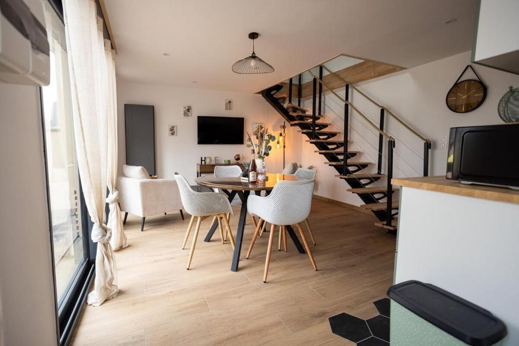 un salon avec une table et des chaises et un escalier dans l'établissement L'avocette Gîtes de la réserve, à Grand-Laviers