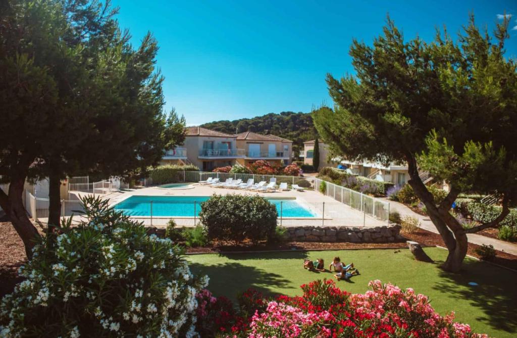 - une vue sur une cour avec une piscine et des arbres dans l'établissement Apparemment RdC climatisé avec piscine, terrasse et parking - App 1502, à Gruissan