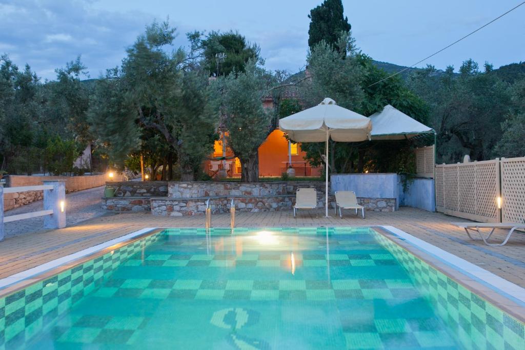 a swimming pool with a patio and an umbrella at Aretousa Studios & Apartments in Skopelos Town