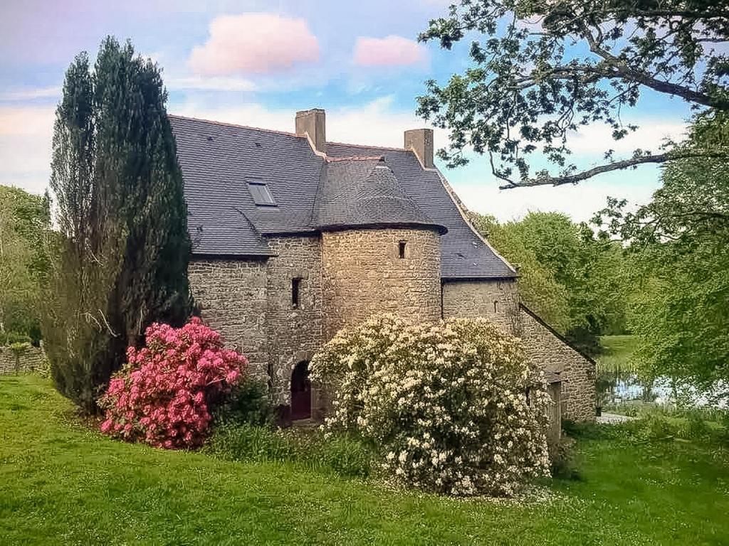 une vieille maison en pierre avec des fleurs devant dans l'établissement Splendide MANOIR - Proche plages - 4 chambres - 3sdb - 8 pers - WIFI, à Plounérin